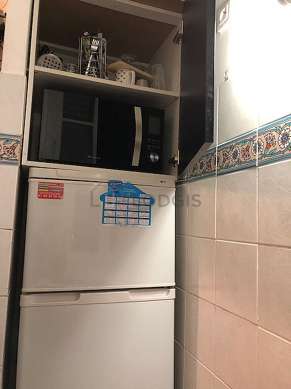 Kitchen equipped with hob, refrigerator, crockery, stool