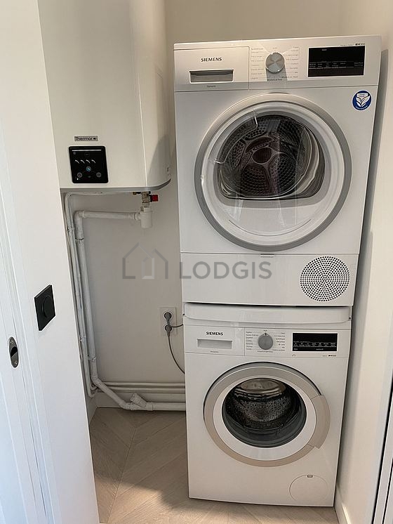 Buanderie avec du parquet au sol et équipée de lave linge, sèche linge