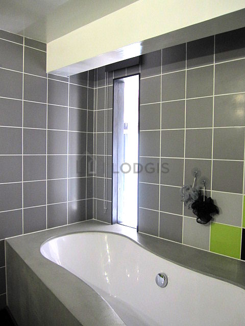 Agréable salle de bain claire avec fenêtres et du parquet au sol