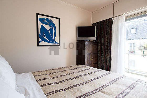 Bright bedroom equipped with tv, bedside table