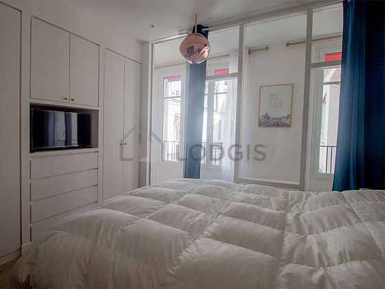 Very bright bedroom equipped with tv, bedside table