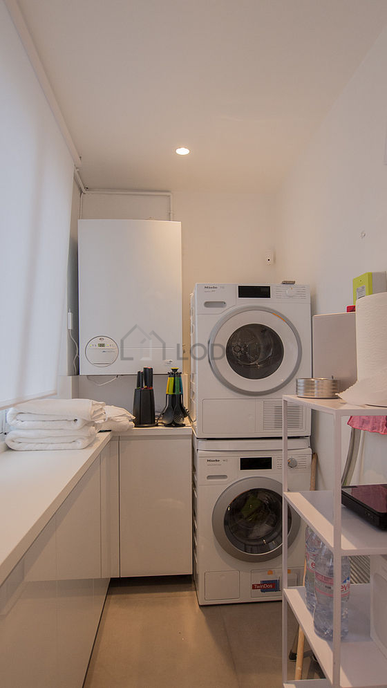 Belle buanderie avec du carrelage au sol et équipée de lave linge, sèche linge