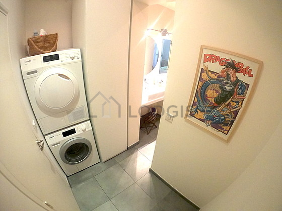Très belle buanderie avec du carrelage au sol et équipée de lave linge, sèche linge