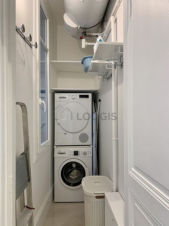 Buanderie avec du parquet au sol et équipée de lave linge, sèche linge