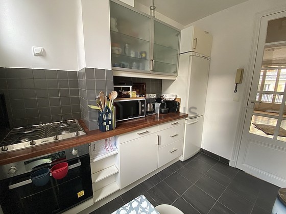 Kitchen equipped with dishwasher, hob, refrigerator, crockery