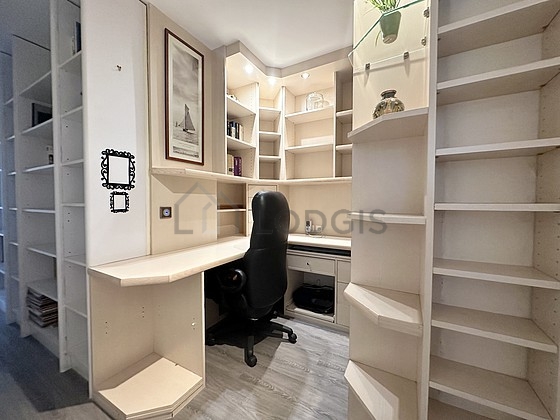 Beautiful office with wooden floor furnished with desk, bookcase, shelves