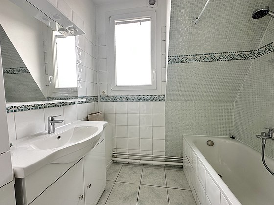 Salle de bain équipée de lave linge, baignoire, radiateur sèche-serviettes