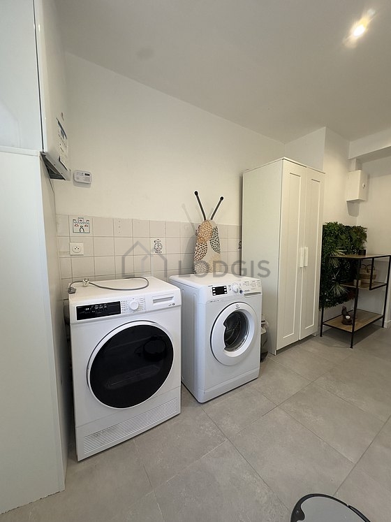 Buanderie avec du carrelage au sol et équipée de lave linge, sèche linge