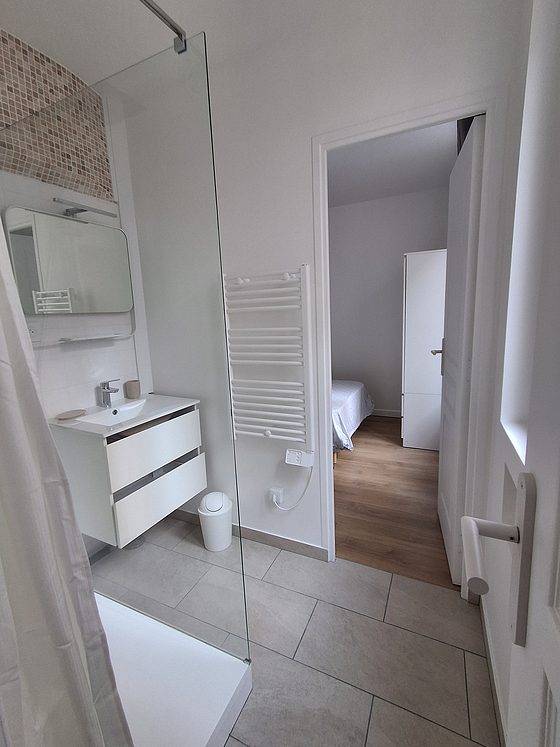 Salle de bain équipée de douche séparée, radiateur sèche-serviettes